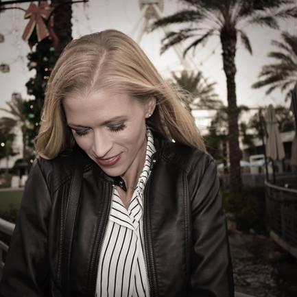 Jessica in a leather jacket smilingwhile looking down